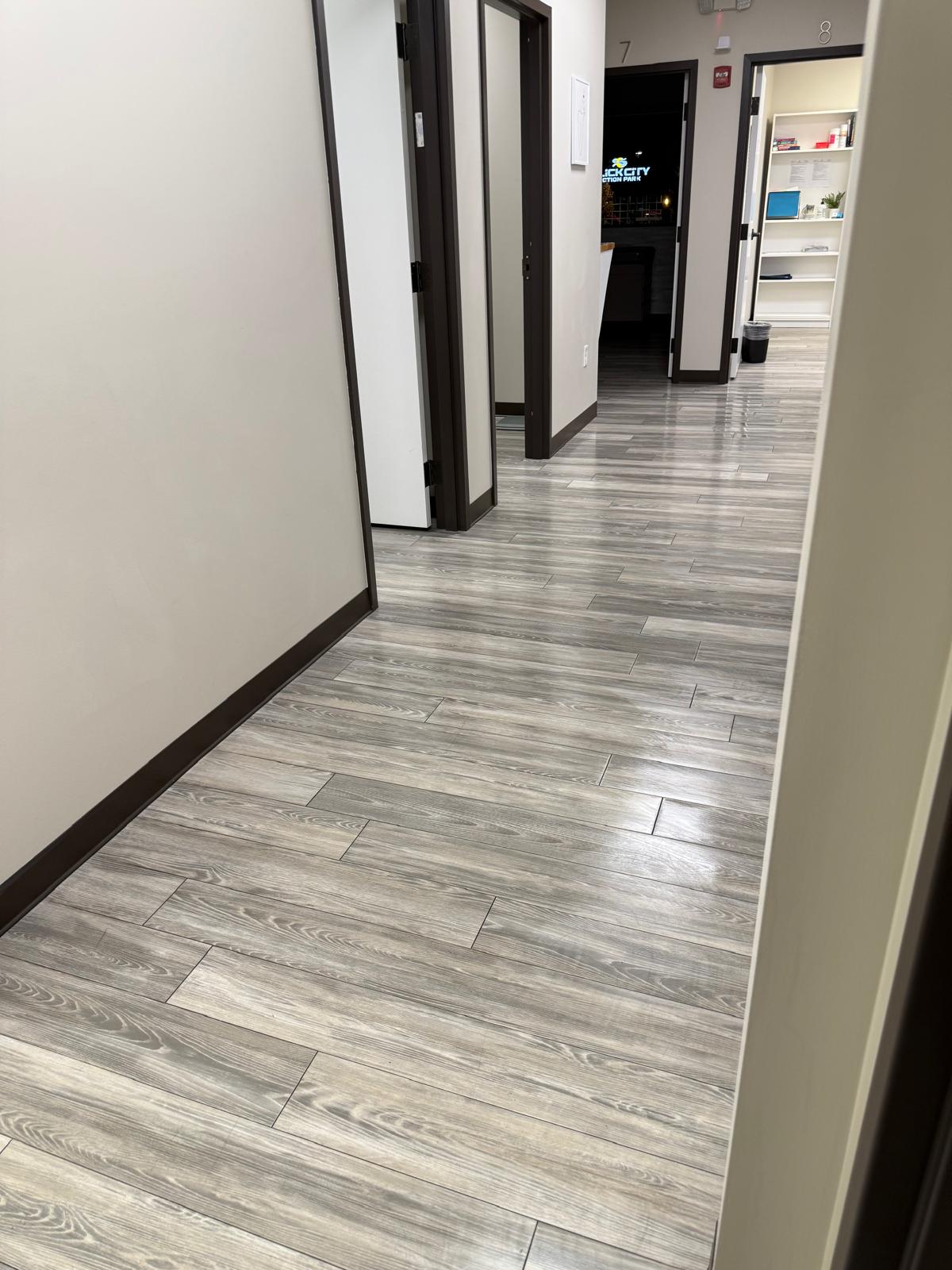 Clinic hallway with gray wood-look flooring and open examination rooms