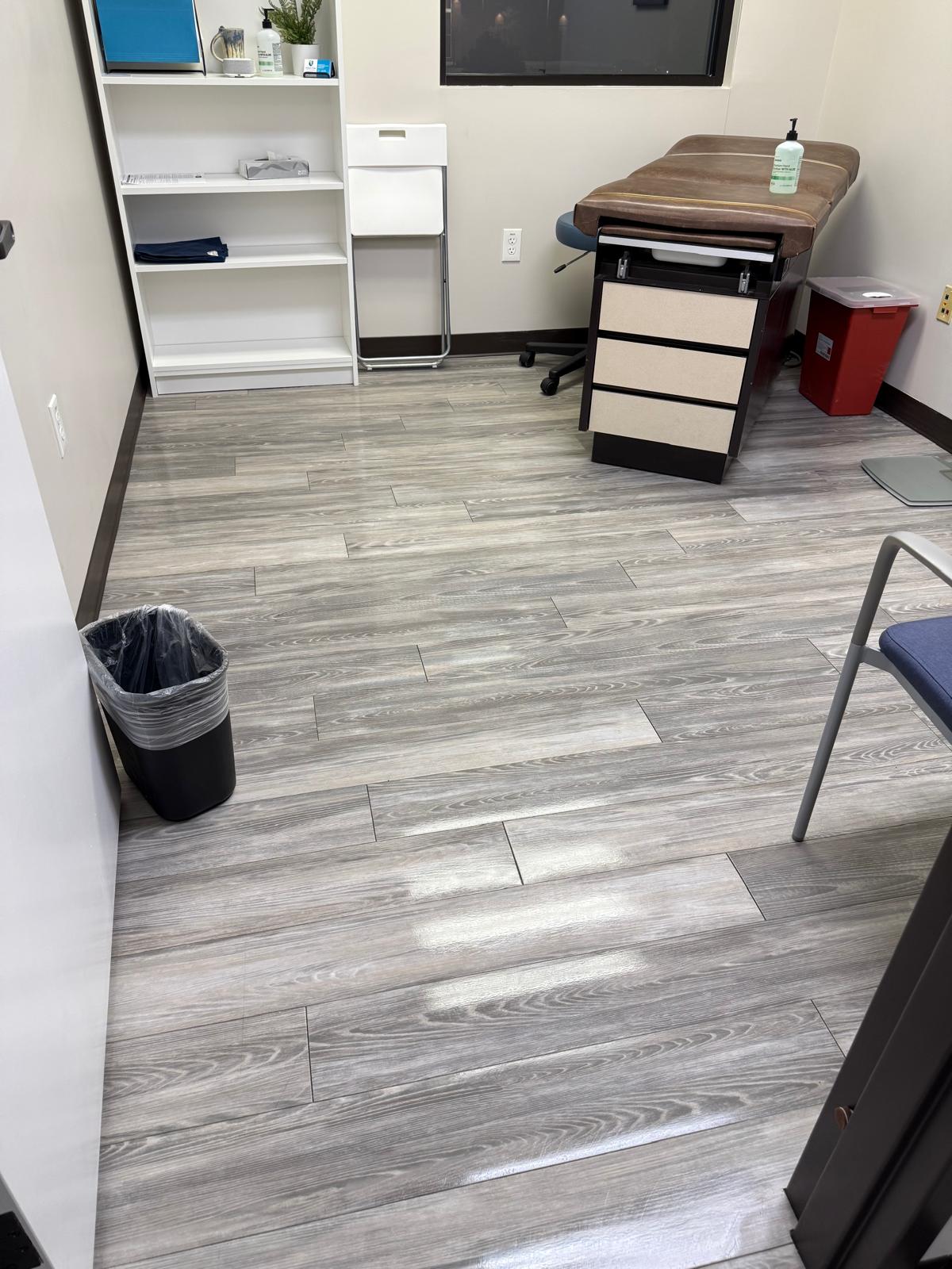 Examination room with shelving, an examination table and reflective gray flooring