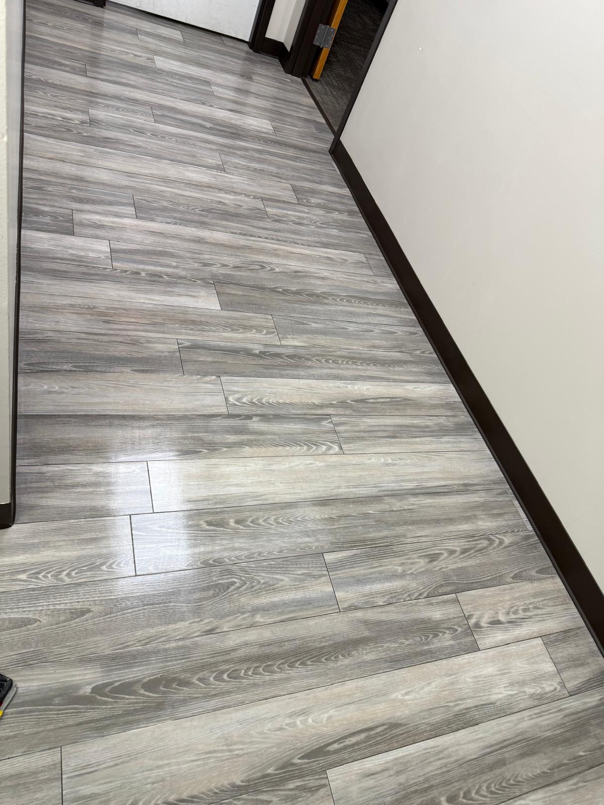 Close view of gray wood-look flooring in a commercial hallway