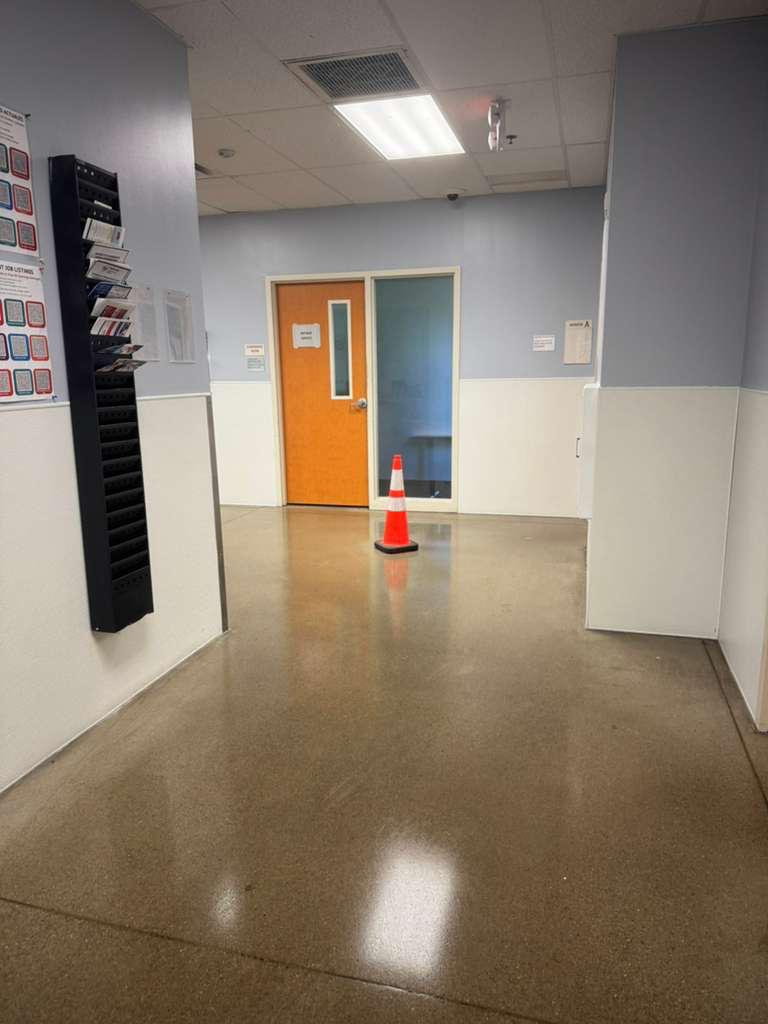Commercial hallway with a reflective floor and safety cone