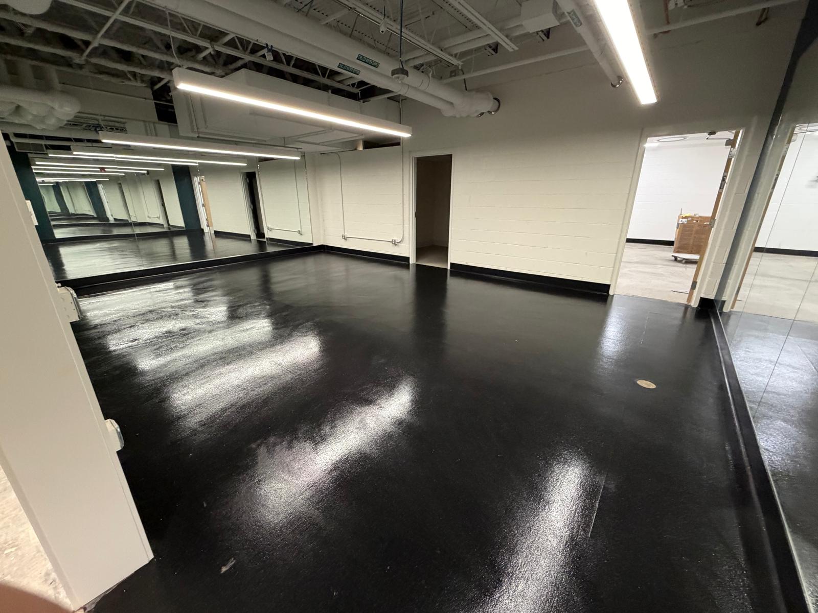 Studio with a dark reflective floor and a wall of mirrors