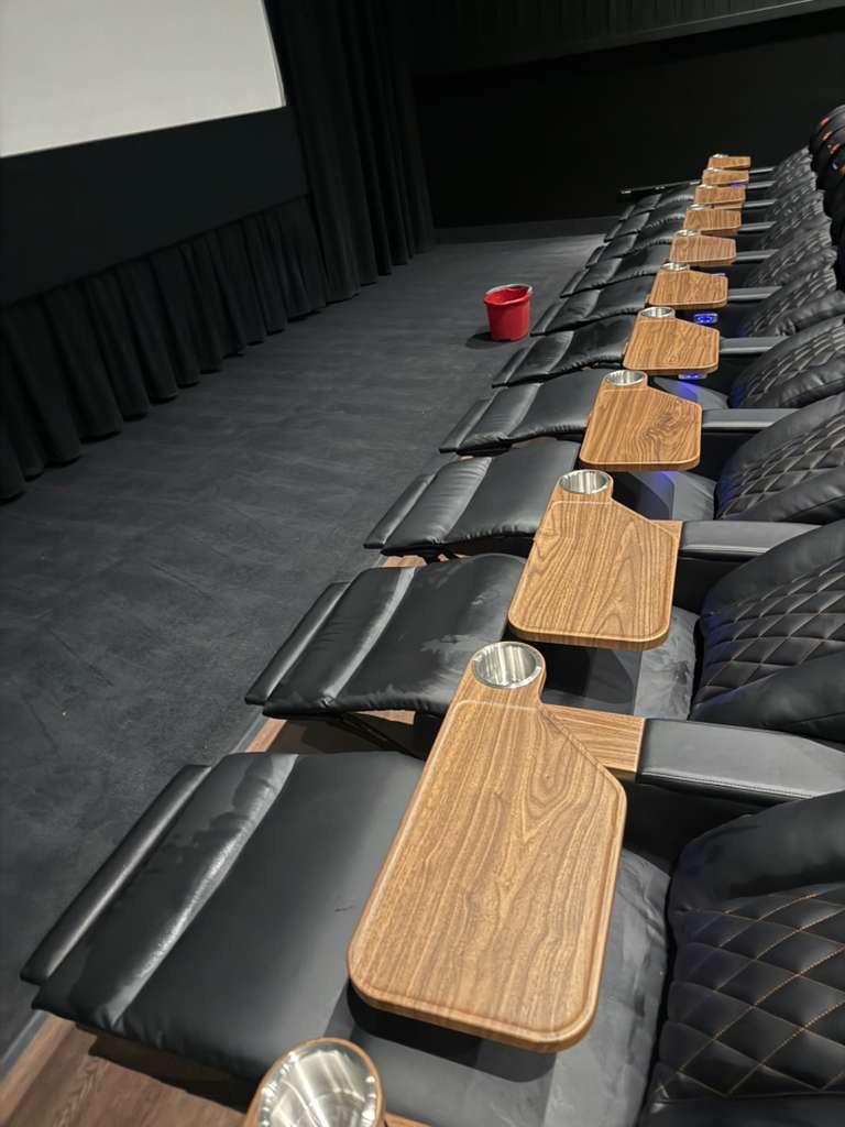 Row of theater seats with individual tables and cup holders